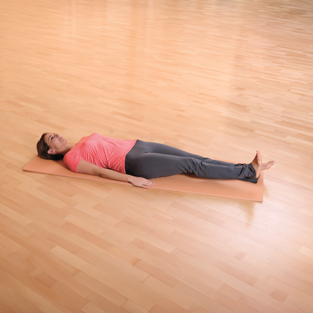 Frau liegt auf dem Rücken auf einer Yogamatte und hebt ein Bein leicht an.